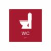 Röd och vit toalett­skylt med piktogram av en toalettstol, texten wc står under symbolen och punktskrift längst ned