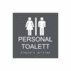 Charcoalgrå och vit skylt för personaltoalett med piktogram av en kvinna och en man åtskilda av ett lodrätt streck, texten personal toalett står under symbolen och punktskrift längst ned