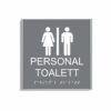 Grå och vit skylt för personaltoalett i storlek 150 x 150 mm med en tunn aluminiumram, med piktogram av en kvinna och en man åtskilda av ett lodrätt streck, texten personal toalett står under symbolen och punktskrift längst ned