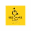 Gul och svart toalettskylt för besökare hwc med piktogram av en rullstol, texten besökare hwc står under symbolen och punktskrift längst ned