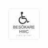 Vit och svart toalettskylt för besökare hwc med piktogram av en rullstol, texten besökare hwc står under symbolen och punktskrift längst ned