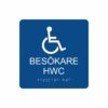 Blå och vit toalettskylt för besökare hwc med piktogram av en rullstol, texten besökare hwc står under symbolen och punktskrift längst ned