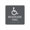 Charcoalgrå och vit toalettskylt för besökare hwc med piktogram av en rullstol, texten besökare hwc står under symbolen och punktskrift längst ned