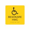 Gul och svart toalettskylt för besökare hwc med piktogram av en rullstol, texten besökare hwc står under symbolen och punktskrift längst ned