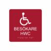 Röd och vit toalettskylt för besökare hwc med piktogram av en rullstol, texten besökare hwc står under symbolen och punktskrift längst ned
