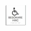Vit och svart toalettskylt för besökare hwc i storlek 150 x 150 mm med en tunn aluminiumram, med piktogram av en rullstol, texten besökare hwc står under symbolen och punktskrift längst ned